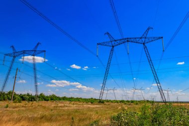 Mavi gökyüzüne karşı yüksek voltajlı güç hattı