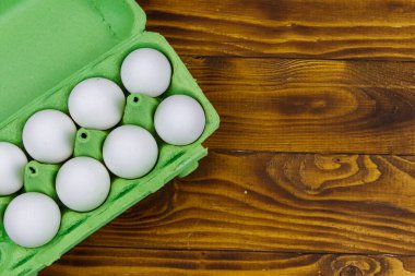 Tahta masadaki karton yumurta kutusunda çiğ tavuk yumurtası. Üst görünüm