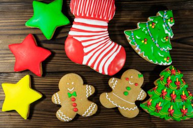 Noel ağacı şeklinde lezzetli Noel kurabiyeleri, zencefilli kurabiye adam, yıldız ve Noel çorabı ahşap masada. Üst görünüm