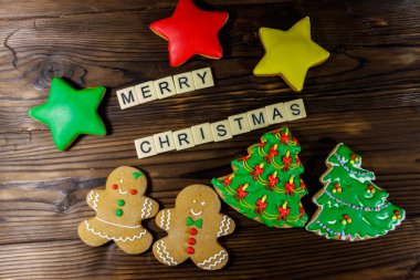 Lezzetli Noel kurabiyeleri ve ahşap masaya yazılmış Mutlu Noeller. Üst görünüm