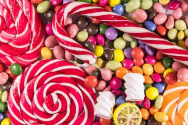 Renkli çikolata şekerlemeleri, lolipoplar, şeker kamışı ve şekerlemelerin arka planı