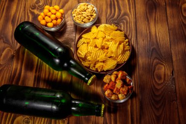 Bira şişeleri ve ahşap masada bira için çeşitli atıştırmalıklar.