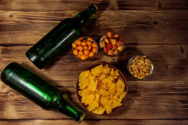 Bira şişeleri ve ahşap masada bira için çeşitli atıştırmalıklar. Üst görünüm