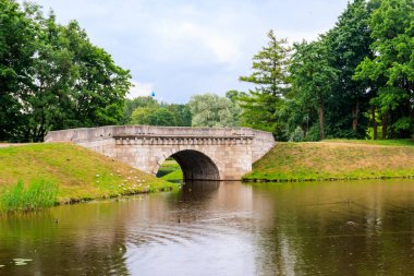 Rusya 'nın Gatchina kentindeki bir gölde taş kemer köprüsü.