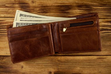 Ahşap masanın üzerinde Amerikan doları olan açık cüzdan. Üstte görüntü