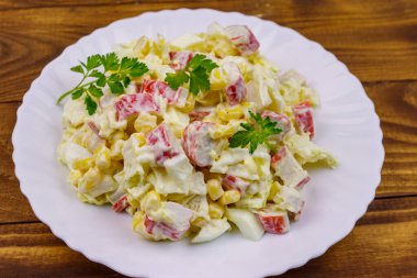 Yengeç saplı salata, tatlı mısır, Çin lahanası, yumurta ve mayonez ahşap masada.