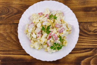 Yengeç saplı salata, tatlı mısır, Çin lahanası, yumurta ve mayonez ahşap masada.