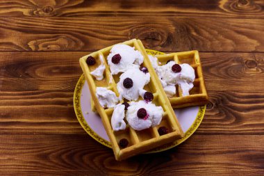 Dondurmalı Belçika waffle 'ı ve ahşap masada böğürtlen.