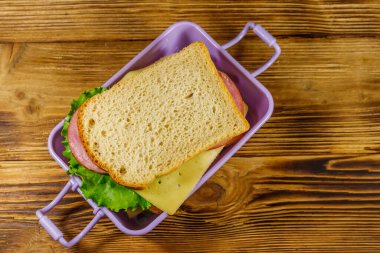 Tahta bir masanın üzerinde sandviçlerle beslenme çantası. Üst görünüm