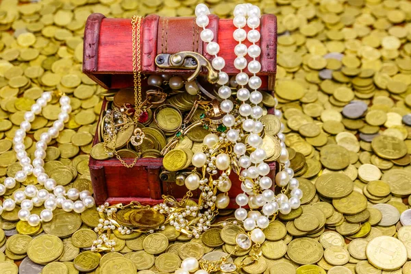 Vintage treasure chest full of gold coins and jewelry on a background of golden coins