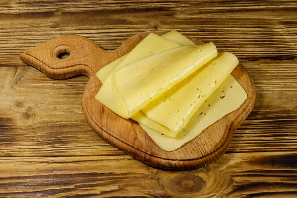 Rebanadas Queso Sobre Tabla Cortar Sobre Mesa Madera —  Fotos de Stock