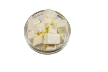 Beyaz arka planda izole edilmiş cam kasedeki Feta peyniri küpleri