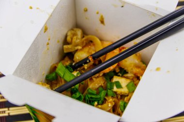 Kızarmış pirinç eriştesi, karidesli Pad Thai ve açık karton pakette tofu. Tayland mutfağı, yemek teslimatı.