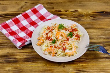 Karidesli makarna, domates sosu ve ahşap masada maydanoz.