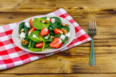 Tahta masada çilekli, ıspanaklı, cevizli ve peynirli taze sağlıklı salata.