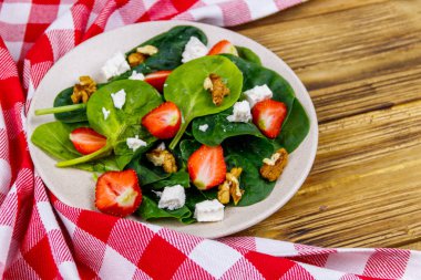 Tahta masada çilekli, ıspanaklı, cevizli ve peynirli taze sağlıklı salata.