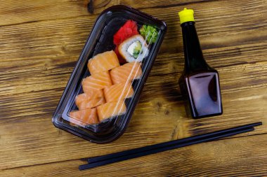 Suşi Philadelphia 'yı tahta masadaki plastik kutuda yuvarlıyor. Üst Manzara. Plastik kabın içinde suşi götürmek ya da teslim etmek için suşi