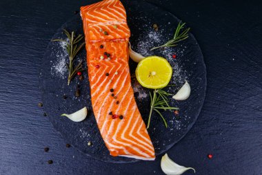 Çiğ somon fileto ve siyah tahta üzerinde baharat. Üst görünüm