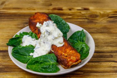 Ahşap masada ıspanaklı ve tartar soslu ızgara somon filetosu.