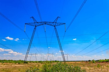Mavi gökyüzüne karşı yüksek voltajlı güç hattı