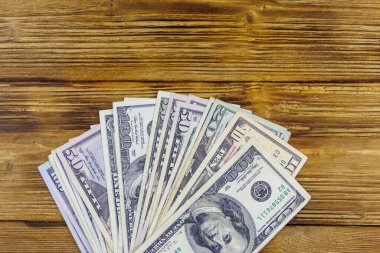 Tahta masanın üzerinde yığınla Amerikan doları var.