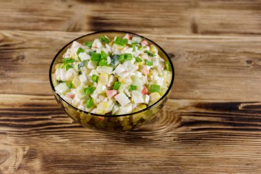 Yengeç çubuklu salata, mısır, salatalık, yumurta, pirinç ve mayonez ahşap masada.