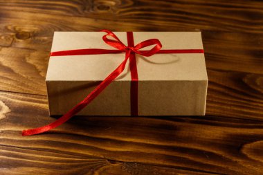 Tahta masadaki kırmızı kurdeleli karton hediye kutusu.