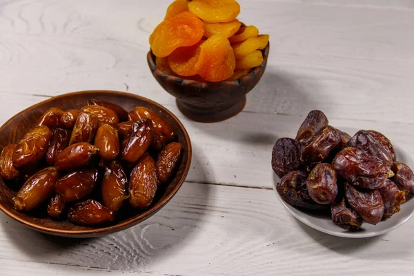 Kurumuş kayısılar ve beyaz ahşap masada meyveler.