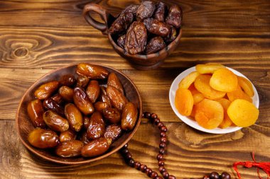 Kurumuş kayısılar ve ahşap masada ahşap tespihli meyveler. Müslümanların kutsal Ramazan bayramı