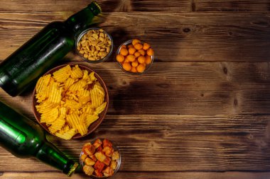 Bira şişeleri ve ahşap masada bira için çeşitli atıştırmalıklar. Üst görünüm, alanı kopyala