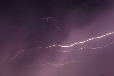 Geceleri karanlık yağmur bulutlarının altında fırtınalı gökyüzünde şimşekler çakar.