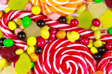 Renkli çikolata şekerleri, lolipoplar, şeker kamışı ve jöleli şekerlerin arka planı