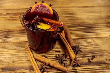 Ahşap masada sıcak şarap ve baharatlar.