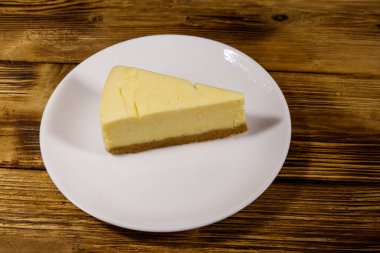 Ahşap masa beyaz bir tabağa lezzetli tatlı New York cheesecake parçası
