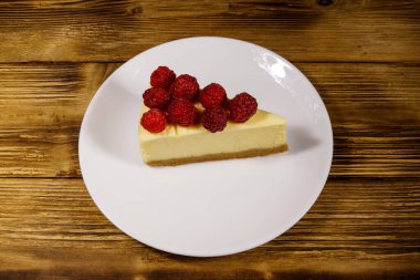 Tahta masadaki beyaz tabakta ahudududulu lezzetli New York peynirli keki.