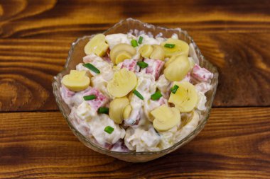 Ahşap masada marine mantar, sosis, soğan ve mayonez ile patates salatası