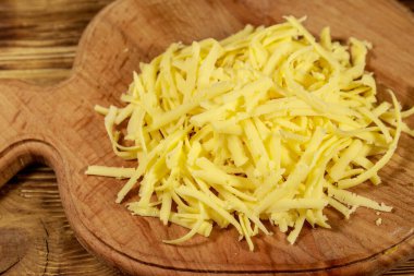 Ahşap masa üzerinde kesme tahtası üzerinde rendelenmiş peynir