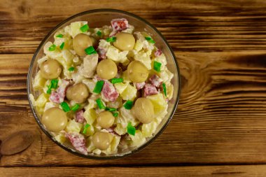 Ahşap masada marine mantar, sosis, soğan ve mayonez ile patates salatası