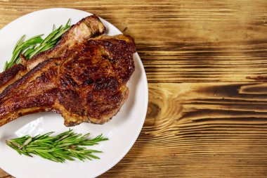Biberiyeli biftek ve beyaz tabakta ahşap masa.