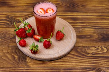 Tahta masada bir bardak taze çilekli smoothie.