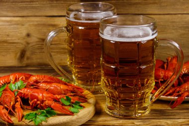 Haşlanmış kerevit ve tahta bir masada iki kupa bira.