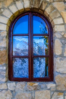 Taş bir duvarda, kemerli ahşap pencere.