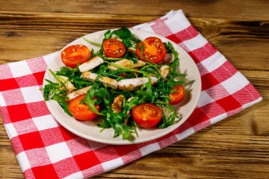 Lezzetli tavuk göğsü salatası, taze roka ve ahşap masada kiraz domatesleri.