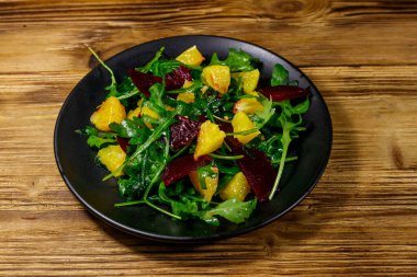 Lezzetli roka salatası, pancar kökü ve portakallar ahşap masada. Sağlıklı gıda veya vejetaryen konsepti