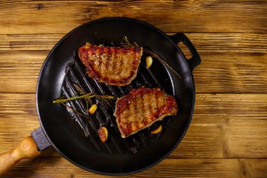 Biberiyeli ızgara domuz bifteği, sarımsak ve ahşap masada ızgara demir tavada baharat. Üst görünüm