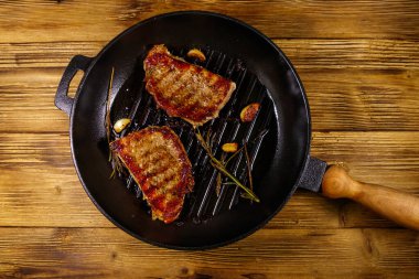 Biberiyeli ızgara domuz bifteği, sarımsak ve ahşap masada ızgara demir tavada baharat. Üst görünüm