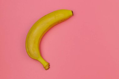 Pembe arka planda sarı muz. Üst görünüm, düz görünüm, minimal dizayn