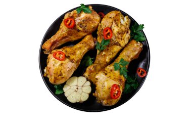 Beyaz arka planda izole edilmiş siyah bir tabakta baharatlı kızarmış tavuk budu. Üst görünüm