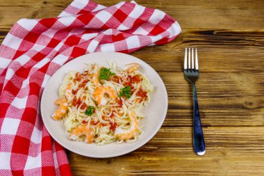 Karidesli makarna, domates sosu ve ahşap masada maydanoz.