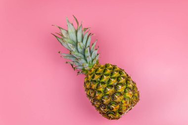 Pembe arka planda koca bir ananas. Üst görünüm